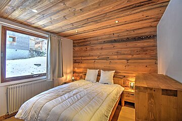 A bedroom with a wooden wall and a bed