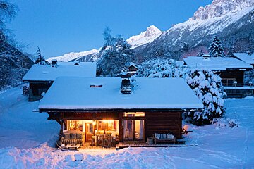 A snowy house with a mountain in the background