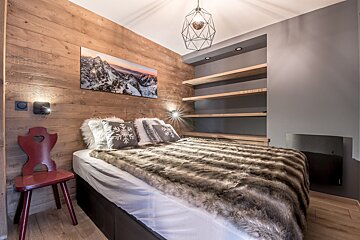 A bedroom with a painting on the wall above the bed