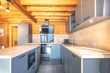 A kitchen with gray cabinets and wooden counter tops
