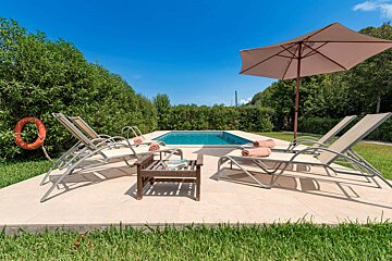 A swimming pool surrounded by chairs and an umbrella