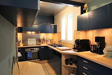 A kitchen with blue cabinets and a black coffee maker
