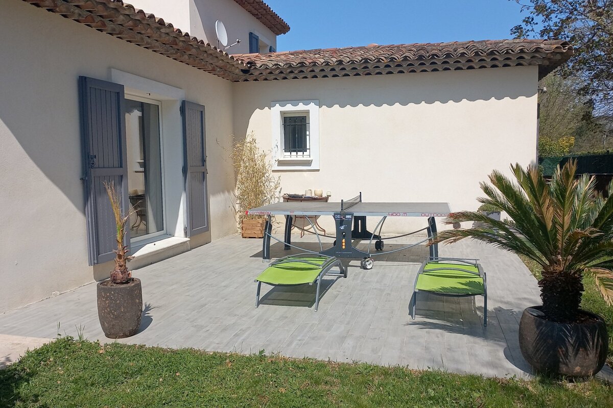 A ping pong table sits on a patio in front of a house