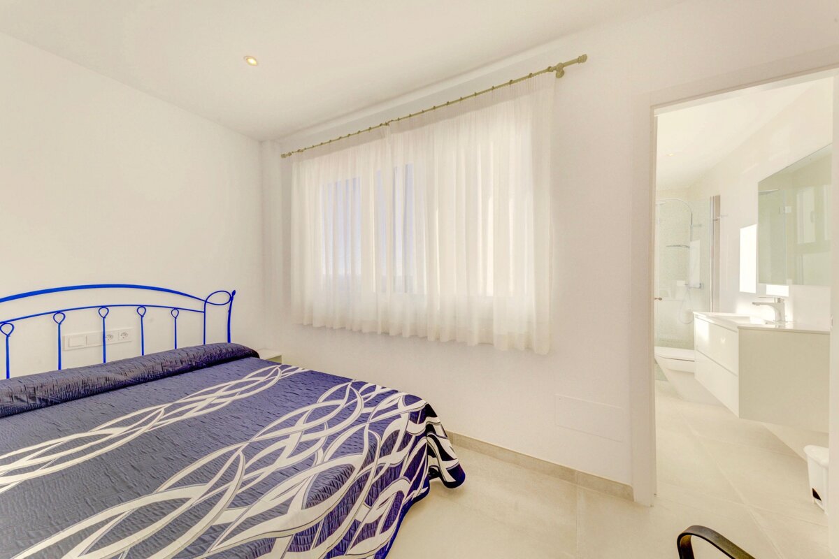 A bedroom with a blue bed and white curtains