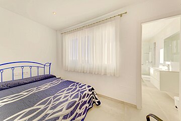 A bedroom with a blue bed and white curtains