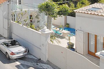 A silver car is parked in front of a white building