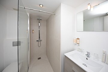 A bathroom with a walk in shower and a sink