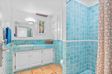 A bathroom with blue tiles and white cabinets