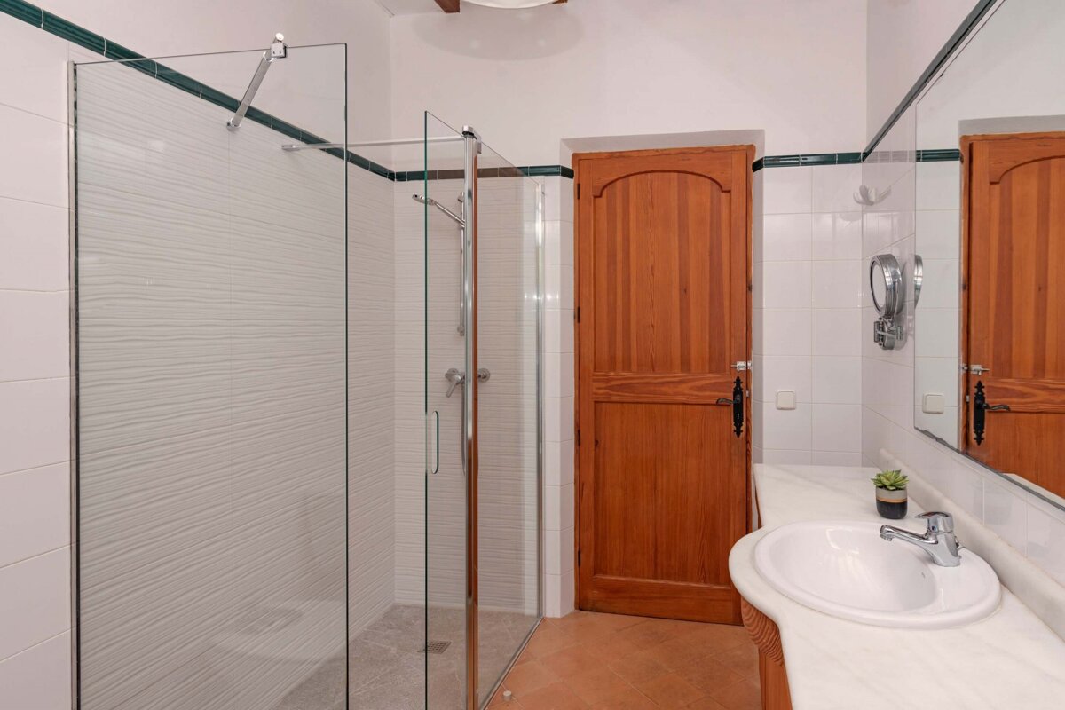 A bathroom with a walk in shower and a sink