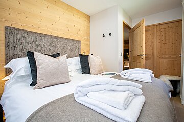 A bed with pillows and towels on it in a bedroom