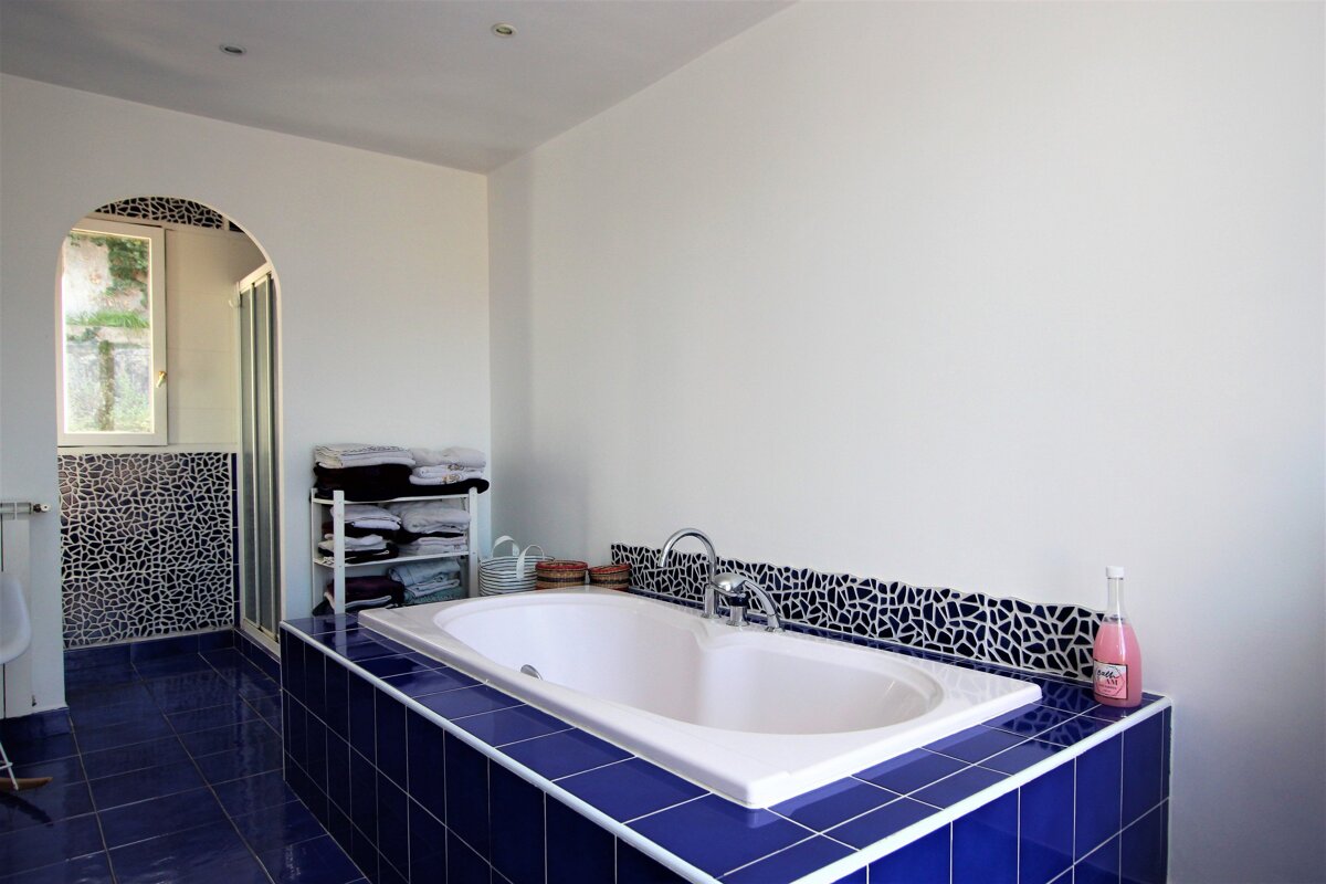 A bathroom with a bathtub surrounded by blue tiles