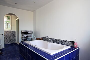 A bathroom with a bathtub surrounded by blue tiles