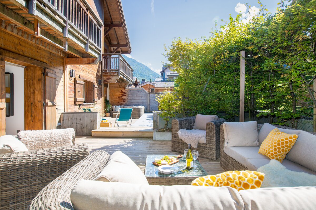 A patio with wicker furniture and a table with a bottle of wine on it