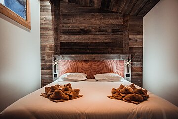 A bed with a wooden headboard and two towels on it