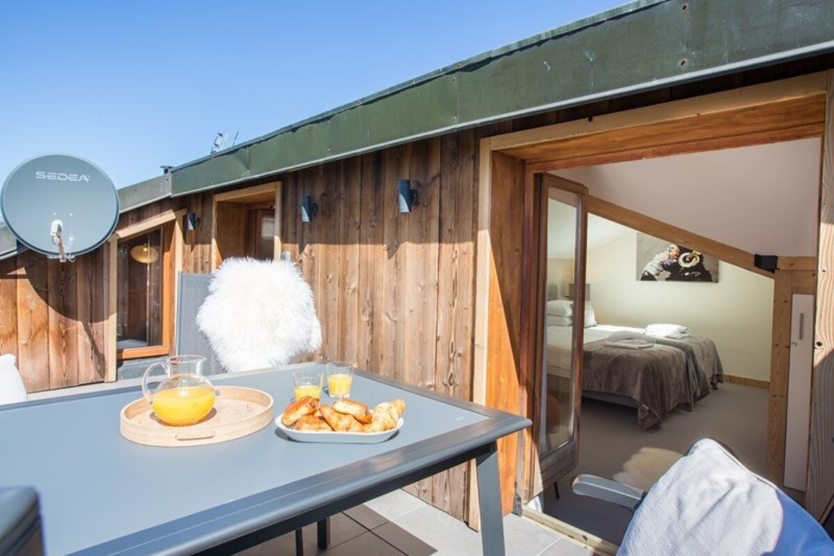 Breakfast served on a sunny wooden balcony looking into a cozy bedroom.