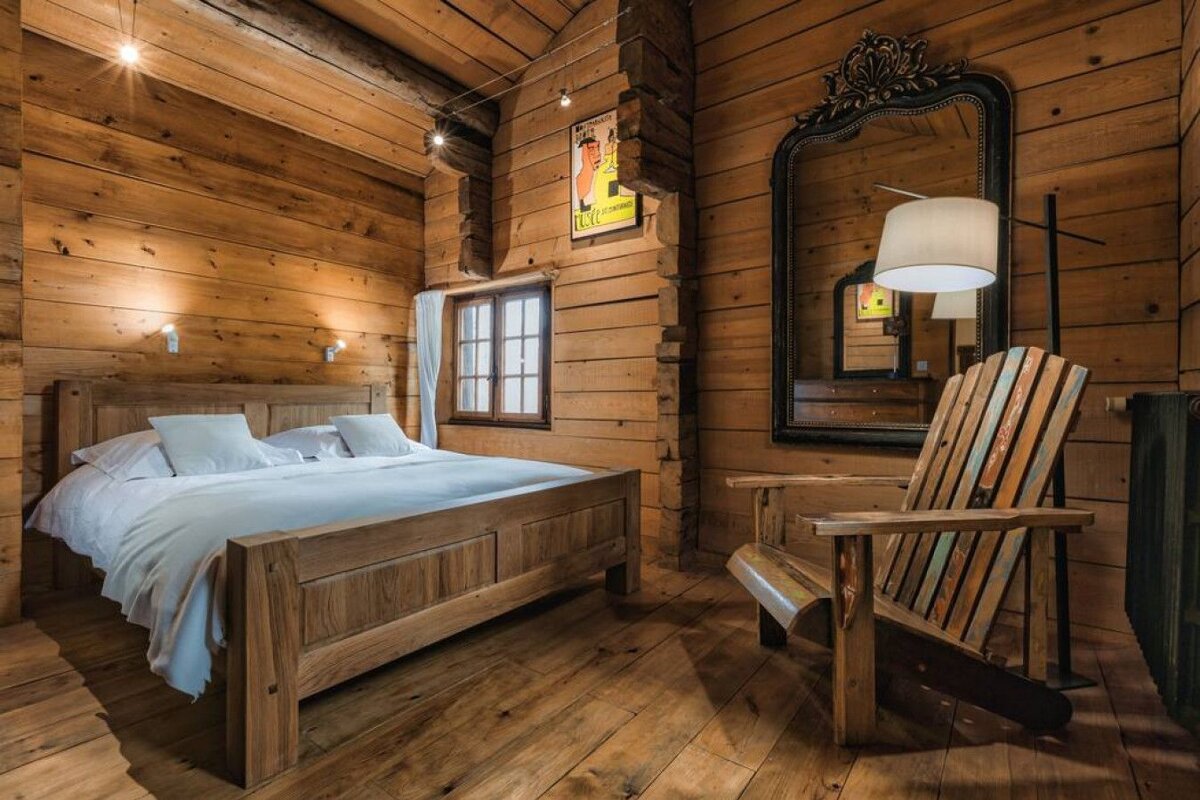 A wooden bedroom with a large bed and a chair