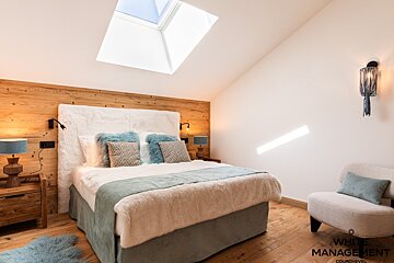 A snowy landscape with a wooden fence and a ski slope in the background
