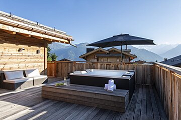 A hot tub on a deck with mountains in the background