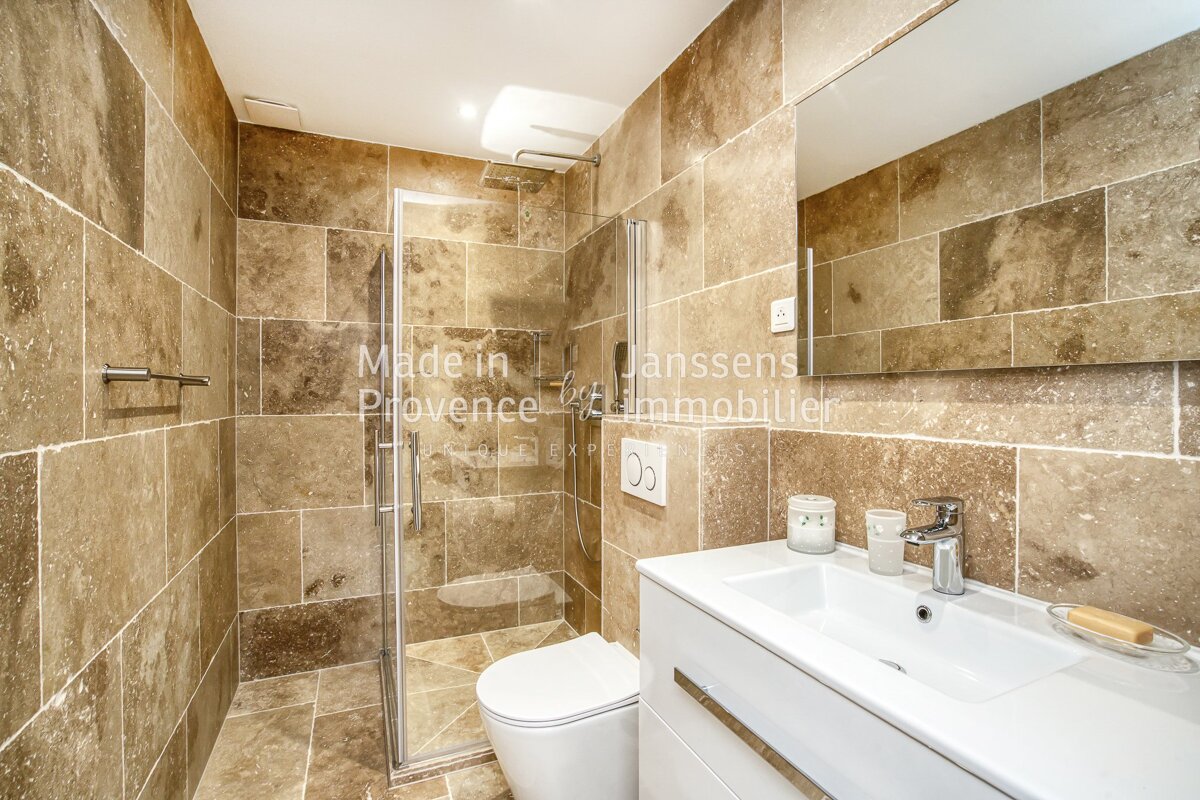 A bathroom with tan tiles and the words made in provence