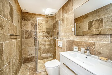 A bathroom with tan tiles and the words made in provence