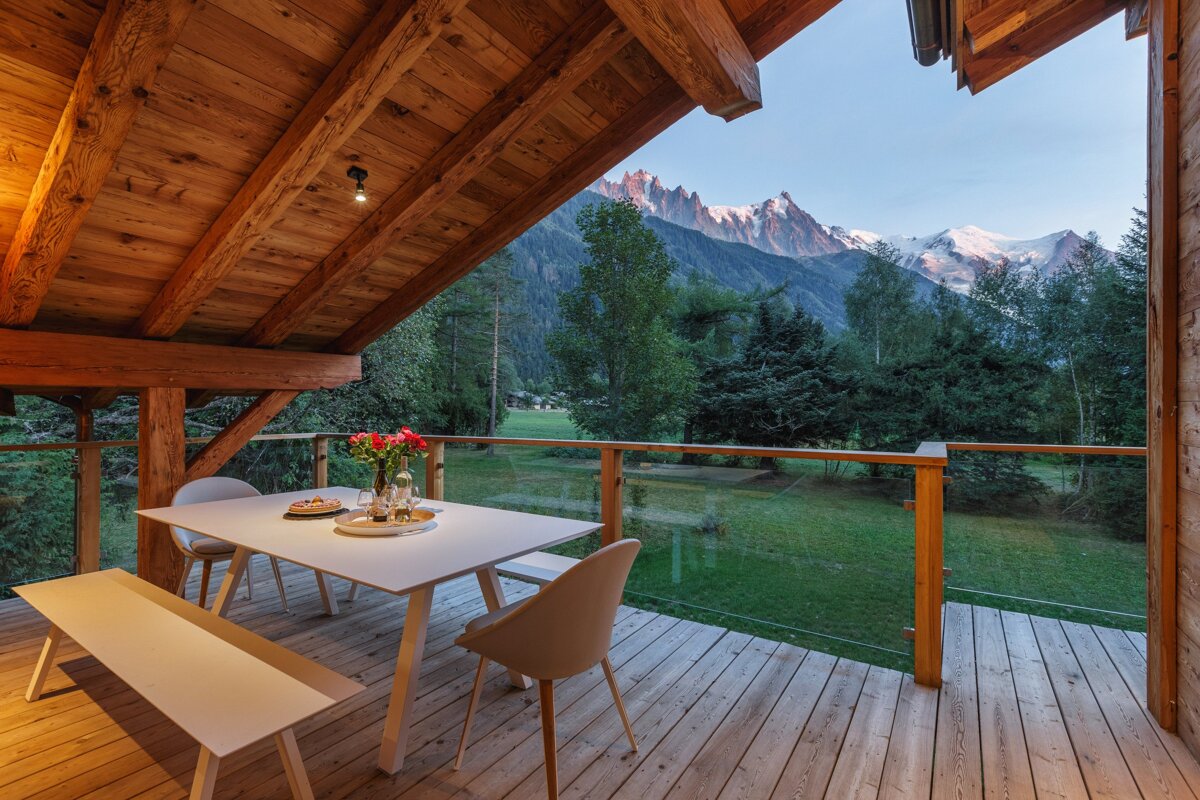 A deck with a table and chairs and a view of mountains