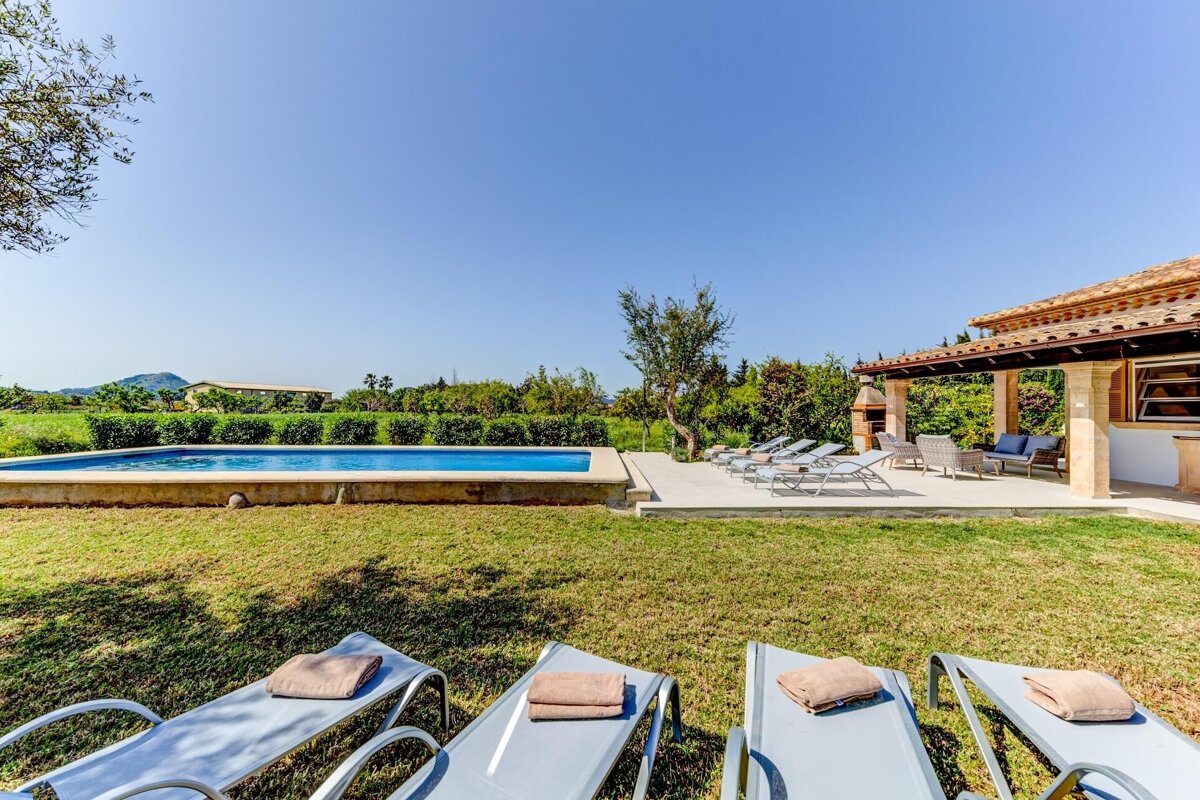 Lawn chairs with towels on them in front of a swimming pool