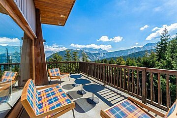 A balcony with chairs and tables overlooking the mountains