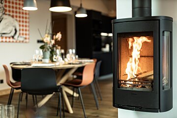 A fireplace in a dining room with a table and chairs in the background
