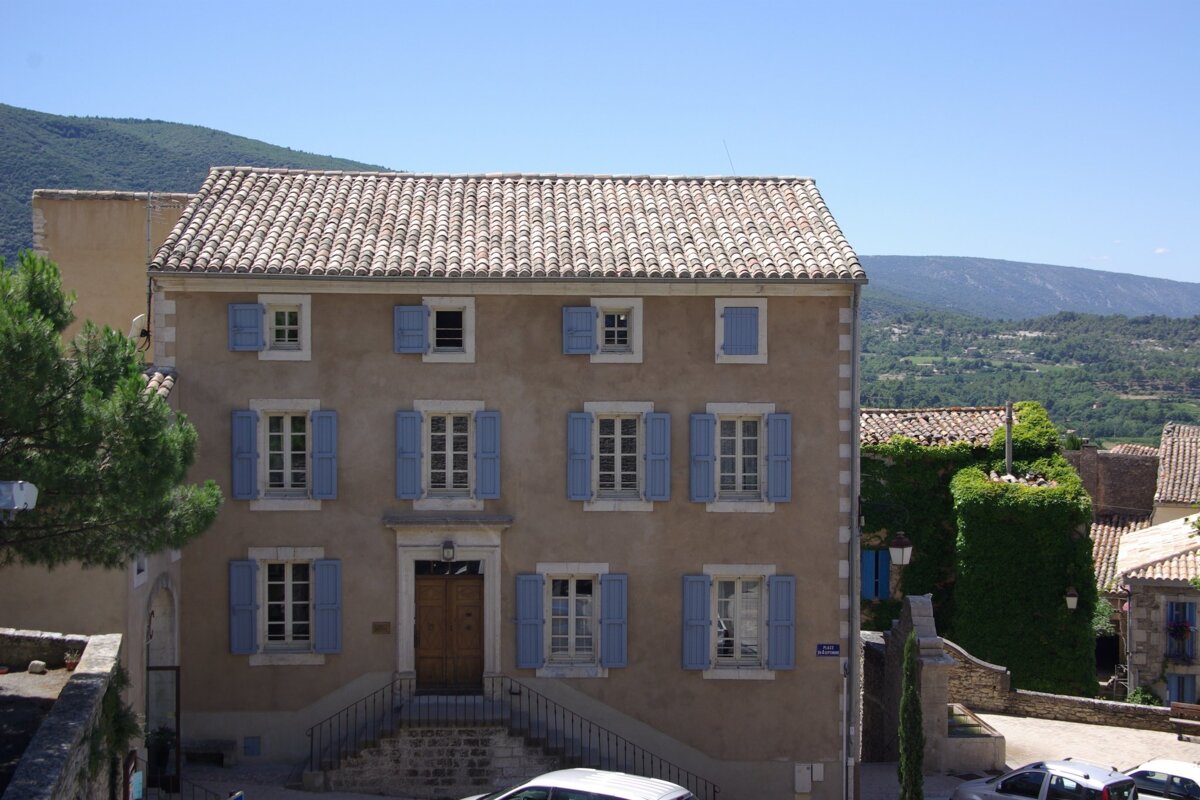 A building with blue shutters and a street sign that says rue