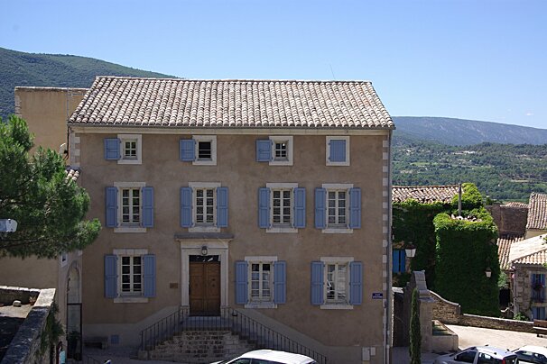 A building with blue shutters and a street sign that says rue