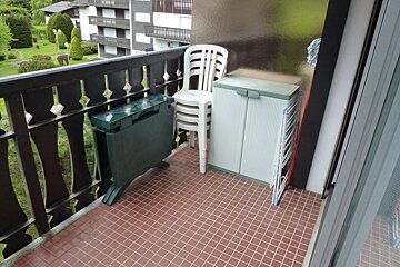 A balcony with a green table and chairs