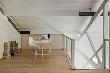 A desk with a laptop on it and a stack of books behind it