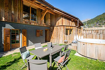 A wooden house with a table and chairs in front of it