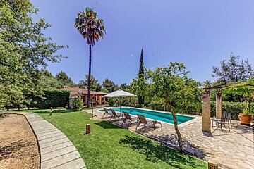 A swimming pool surrounded by chairs and umbrellas with a house in the background