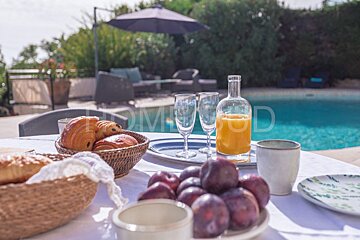 A bottle of orange juice sits on a table in front of a pool