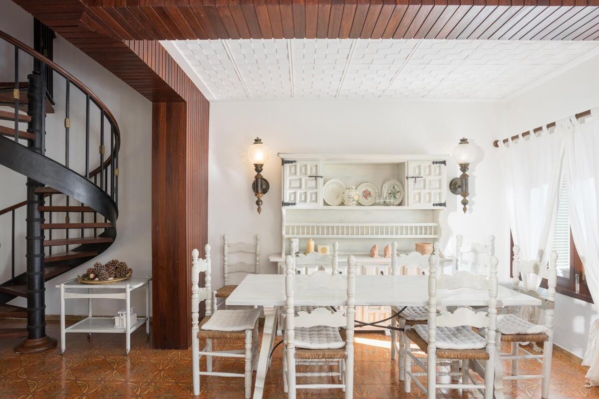 A dining room with a table and chairs and a spiral staircase