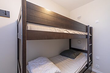 A bunk bed with a white mattress and a grey pillow