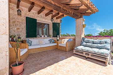 A patio with wicker furniture and green shutters