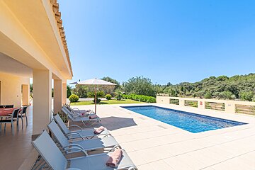 A large swimming pool is surrounded by chairs and umbrellas