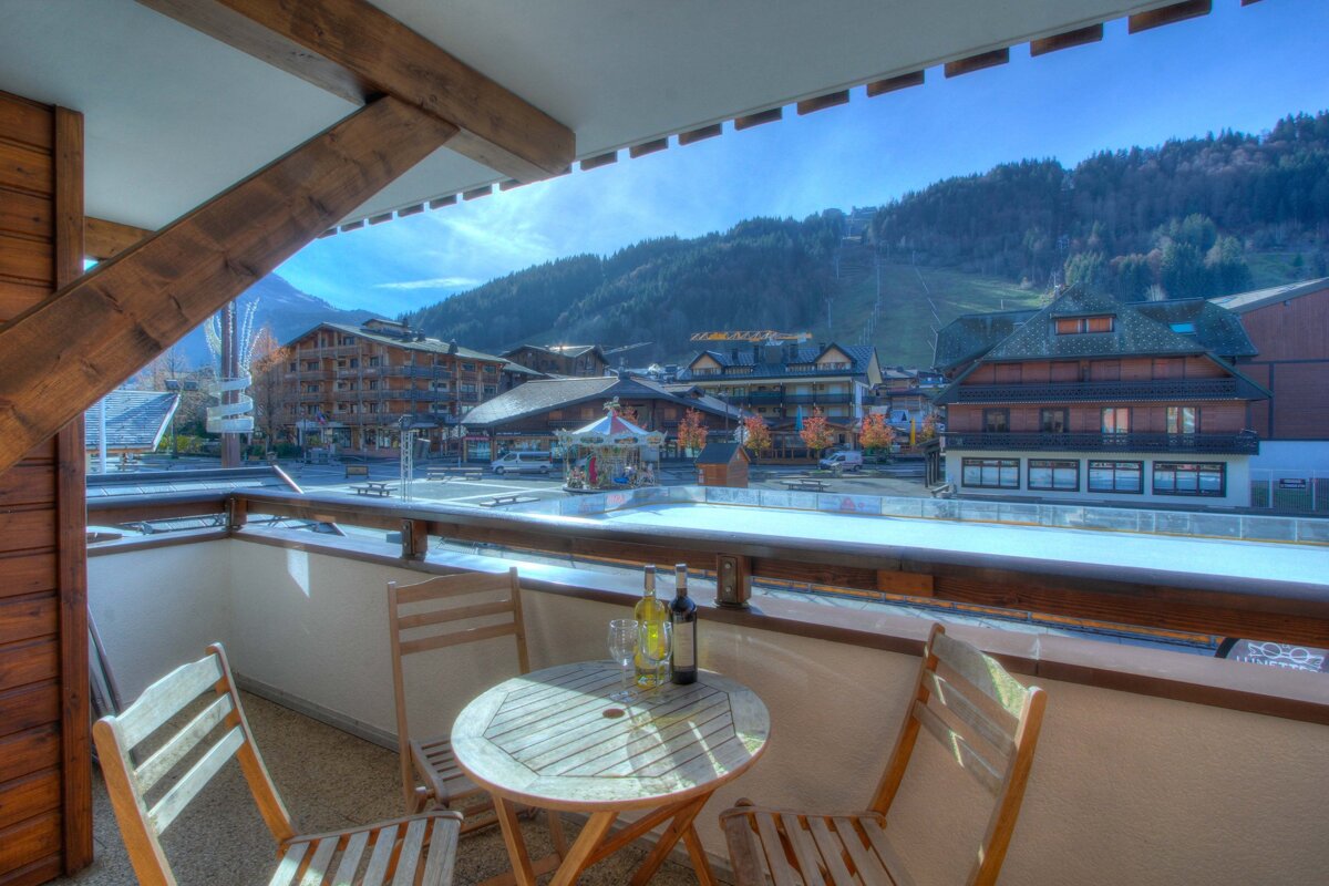 Two bottles of wine sit on a table in front of a view of a ski resort