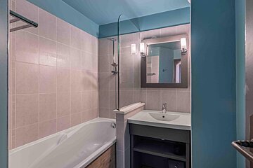 A bathroom with a bathtub sink and mirror