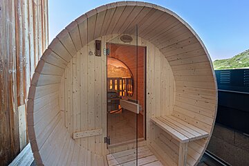 A wooden barrel shaped sauna with a glass door