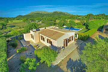 An aerial view of a house with a pool and mountains in the background