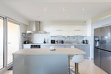 A kitchen with white cabinets and a stainless steel refrigerator
