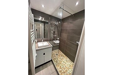 A bathroom with a walk in shower and a sink