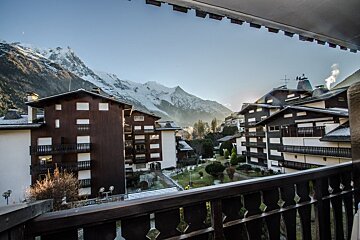 A balcony overlooking a ski resort with mountains in the background
