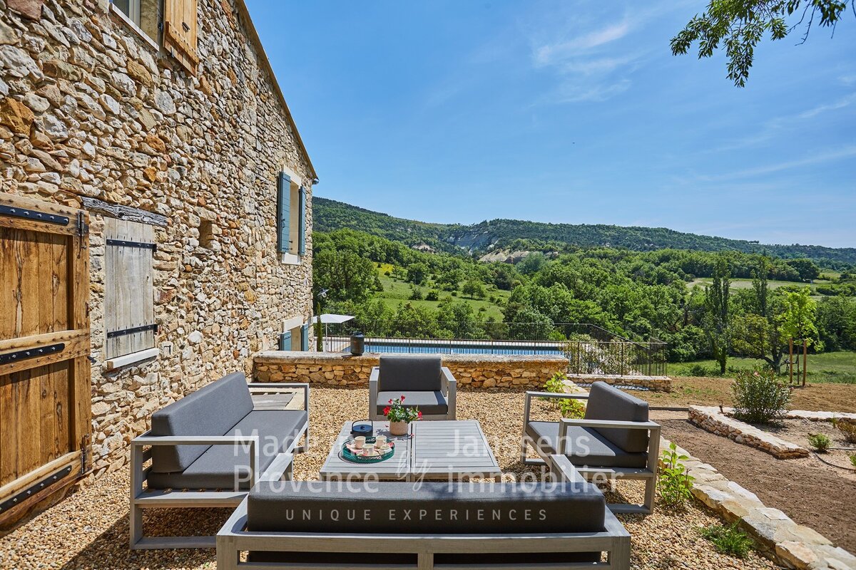 A patio with a couch and chairs in front of a stone building that says unique experiences