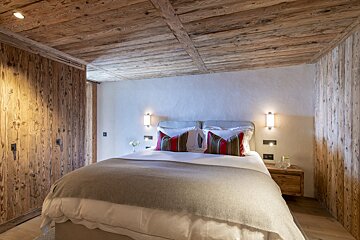 A bedroom with a wooden ceiling and a bed