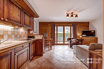 A kitchen with wooden cabinets and a television from mountain base