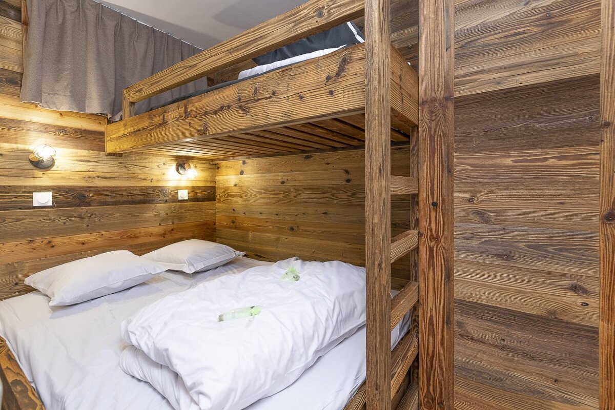 A wooden bunk bed with white sheets and pillows
